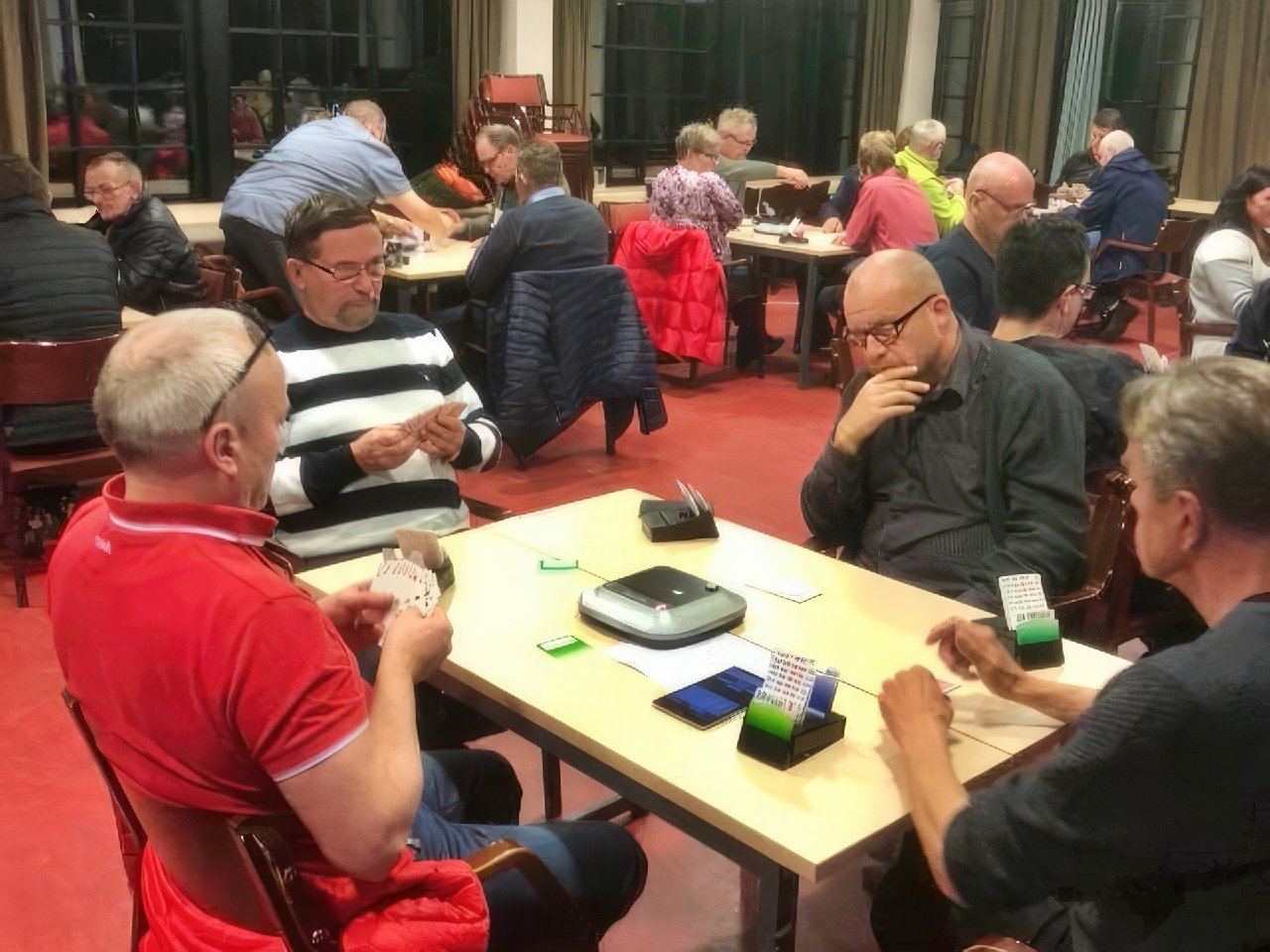 A busy room full of bridge tables during an event.
